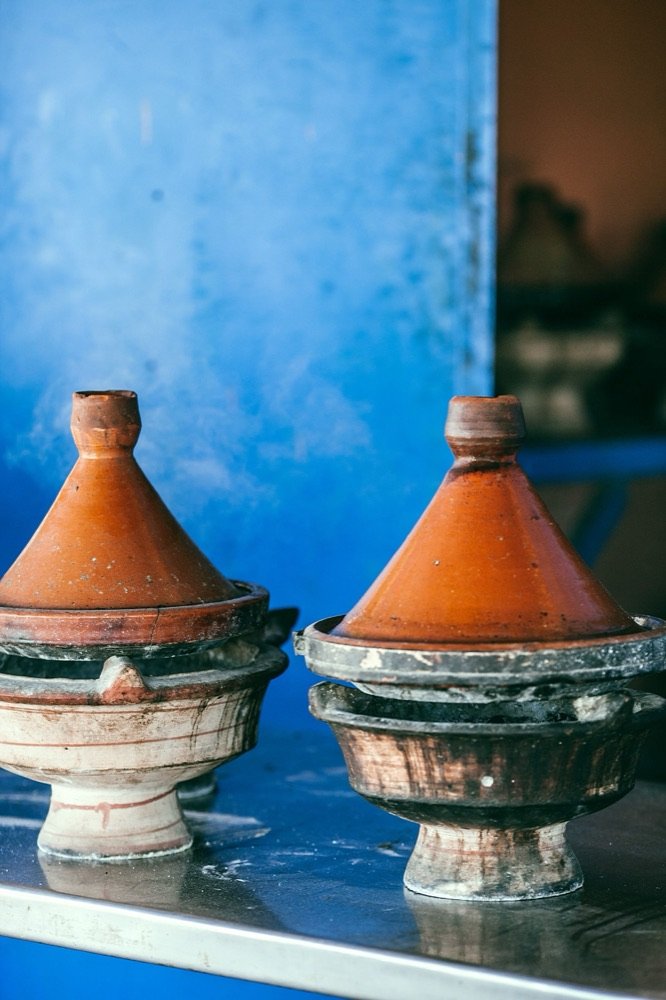 Dos tajines de barro sobre una pared azul.